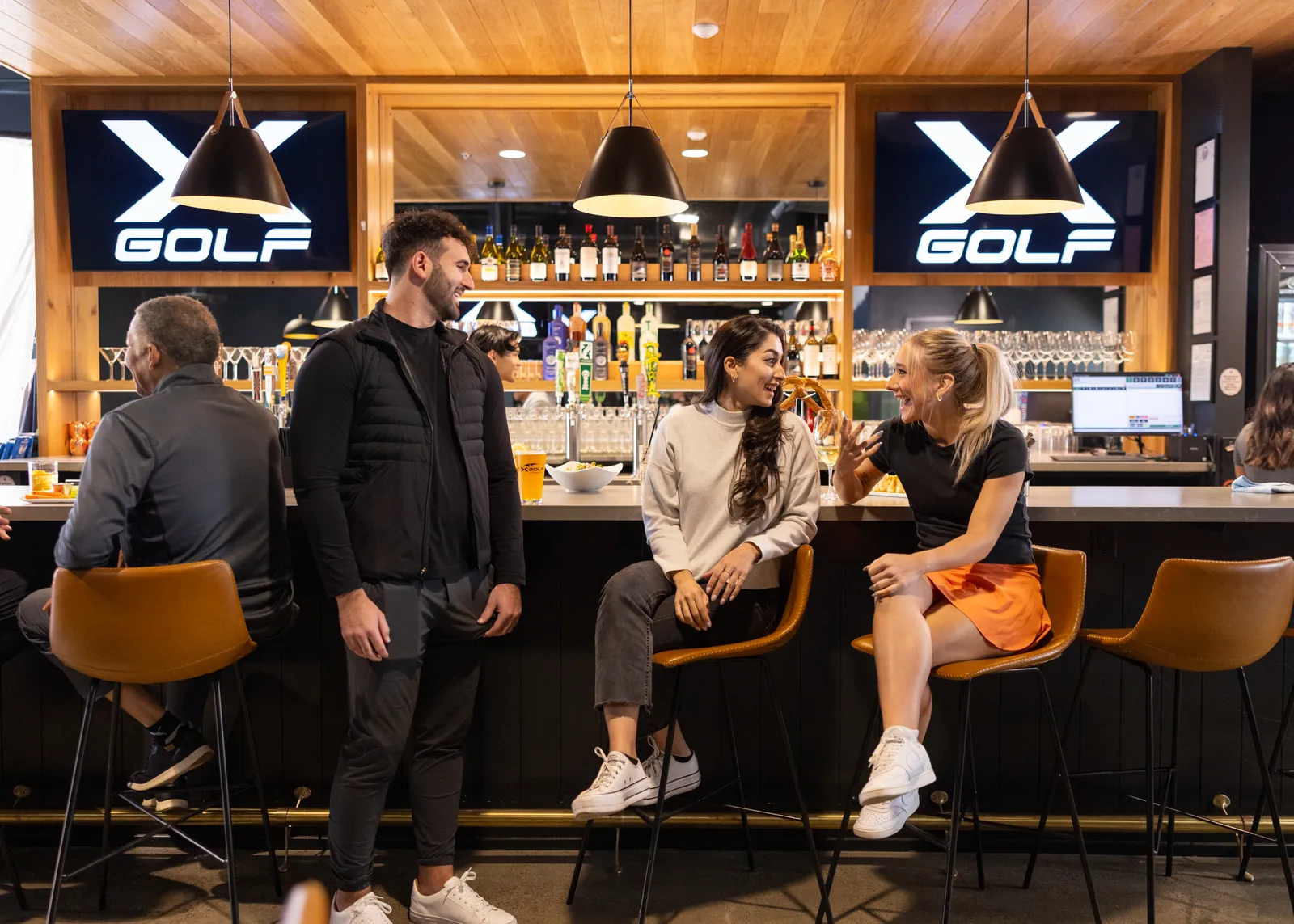 Person smiles while wearing the tee at X-Golf.